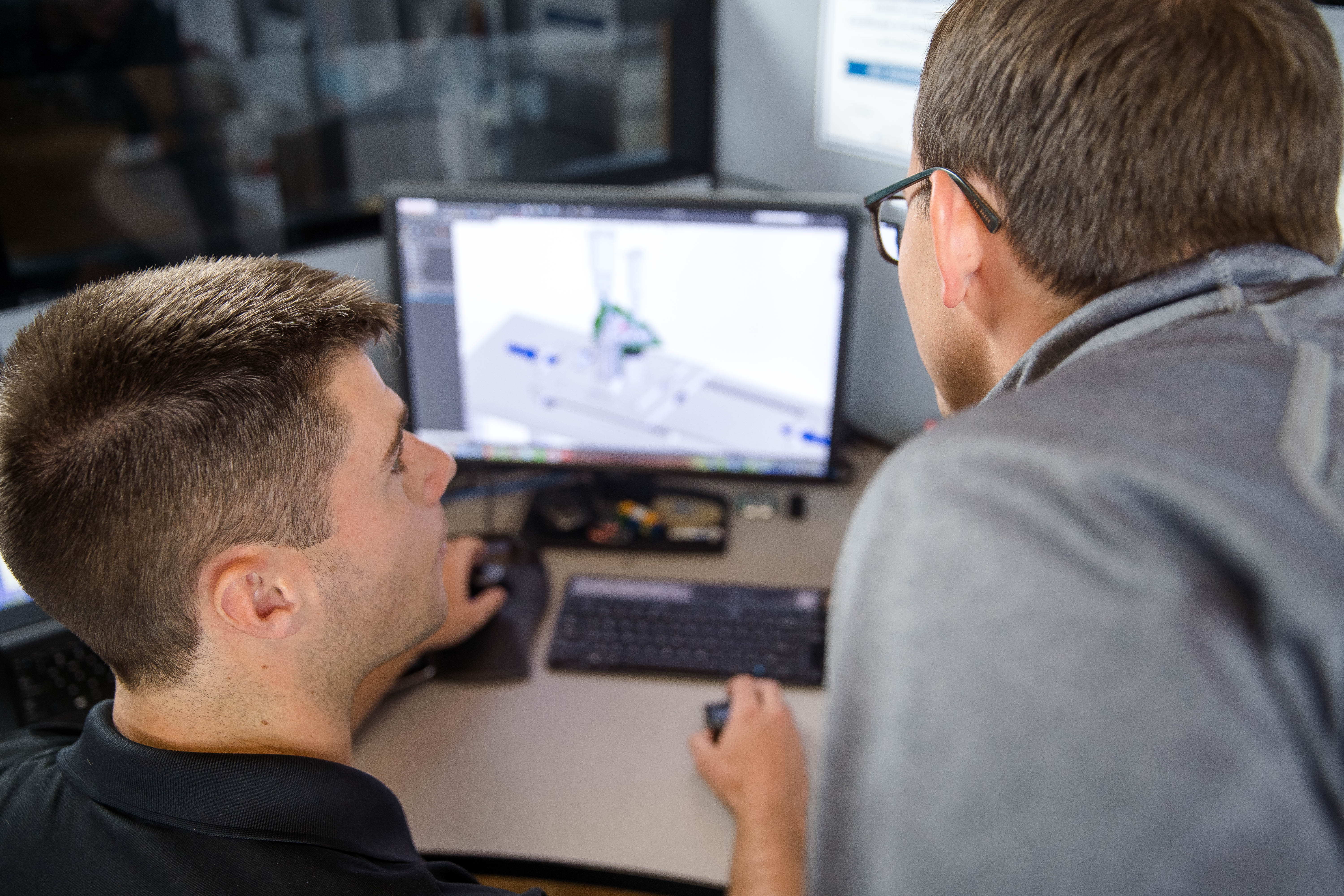 Two engineers looking at a CAD model on computer